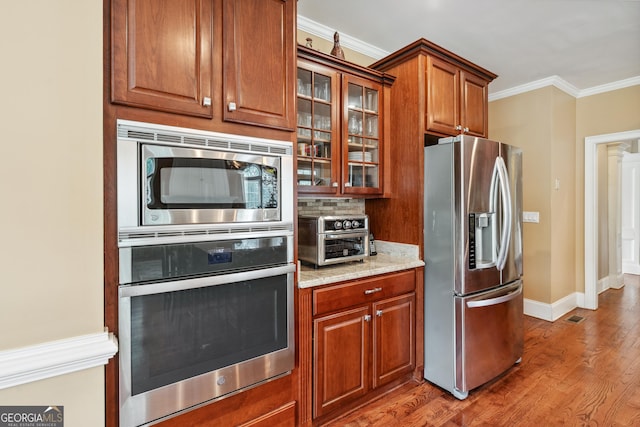 106 April Walk, Mcdonough, GA 30253 - kitchen with stainless steel appliances, light wood-style floors, light stone countertops, glass insert cabinets, and brown cabinetry