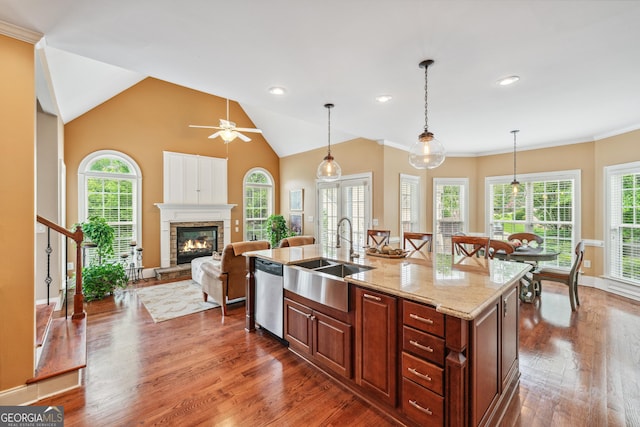 106 April Walk, Mcdonough, GA 30253 - kitchen with stainless steel dishwasher, dark wood finished floors, a center island with sink, a fireplace, and decorative light fixtures