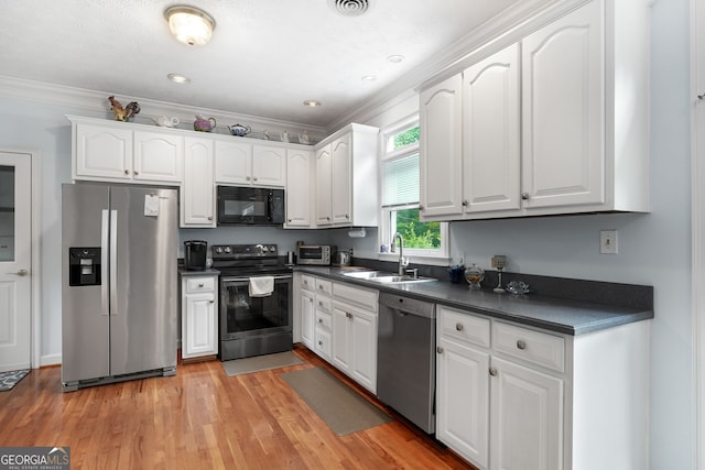 150 Tramore Trce, Tyrone, GA 30290 - kitchen featuring appliances with stainless steel finishes, dark countertops, white cabinetry, crown molding, and light wood-type flooring