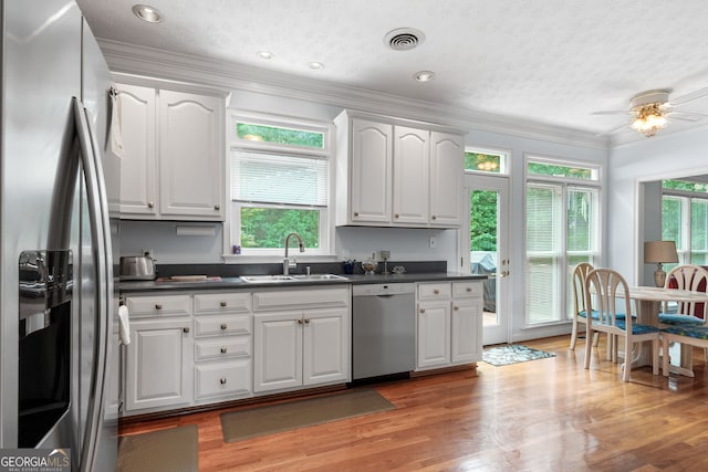 150 Tramore Trce, Tyrone, GA 30290 - kitchen featuring appliances with stainless steel finishes, ornamental molding, dark countertops, white cabinetry, and light wood-style floors