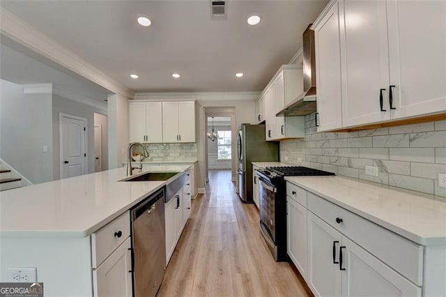 6867 Kate, Flowery Branch, GA 30542 - kitchen with appliances with stainless steel finishes, wall chimney range hood, crown molding, white cabinets, and light wood-style floors