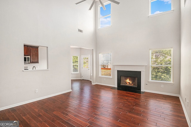 915 Pebble Creek Trl, Suwanee, GA 30024 - unfurnished living room featuring a ceiling fan, dark wood-style floors, a high ceiling, and healthy amount of natural light