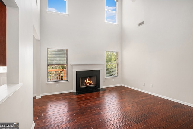 915 Pebble Creek Trl, Suwanee, GA 30024 - unfurnished living room featuring a towering ceiling, dark wood finished floors, plenty of natural light, and a fireplace with flush hearth