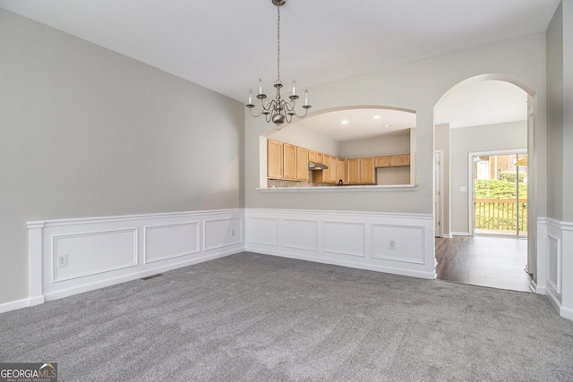 801 Tulip Poplar Way Unit 2501, Lawrenceville, GA 30044 - unfurnished dining area featuring dark carpet, a chandelier, arched walkways, and a wainscoted wall