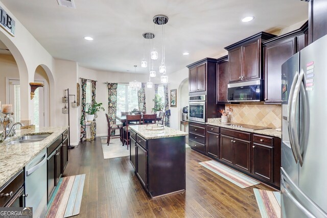 312 Sierra Ct, Mcdonough, GA 30253 - kitchen with appliances with stainless steel finishes, light stone countertops, arched walkways, a center island, and recessed lighting