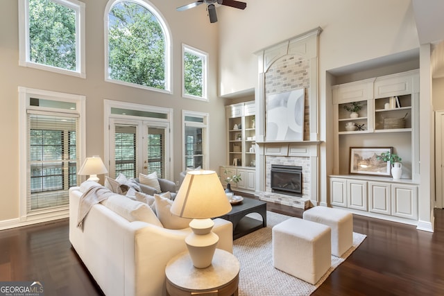 110 Wellington Way, Canton, GA 30115 - living area with a towering ceiling, a ceiling fan, dark wood finished floors, a glass covered fireplace, and built in features