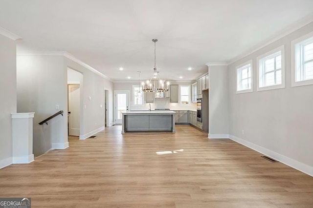 148 Palm St, Holly Springs, GA 30115 - kitchen featuring a chandelier, ornamental molding, a kitchen island with sink, open floor plan, and light wood-style floors