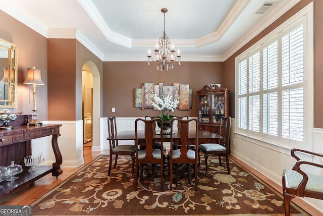1071 Creekwood Cir, Madison, GA 30650 - dining space with a chandelier, arched walkways, wood finished floors, a wainscoted wall, and ornamental molding