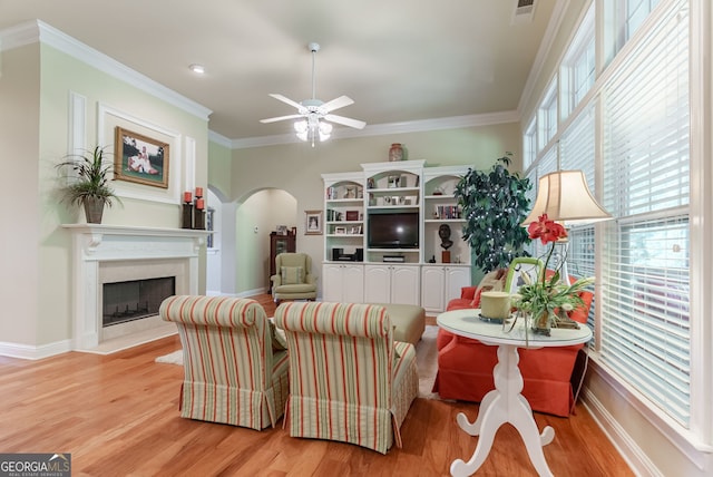 1071 Creekwood Cir, Madison, GA 30650 - living room featuring arched walkways, ceiling fan, light wood finished floors, crown molding, and a fireplace