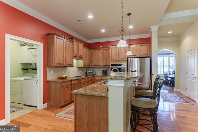 1071 Creekwood Cir, Madison, GA 30650 - kitchen with appliances with stainless steel finishes, washing machine and dryer, brown cabinets, crown molding, and recessed lighting