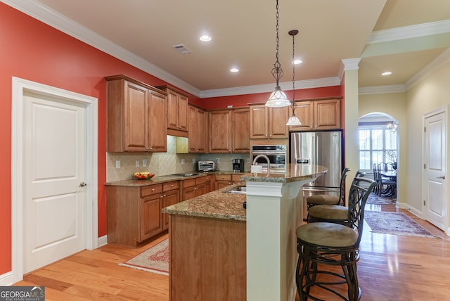 1071 Creekwood Cir, Madison, GA 30650 - kitchen with appliances with stainless steel finishes, brown cabinetry, light wood finished floors, crown molding, and recessed lighting