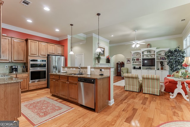1071 Creekwood Cir, Madison, GA 30650 - kitchen featuring stainless steel appliances, arched walkways, light wood-style floors, crown molding, and open floor plan