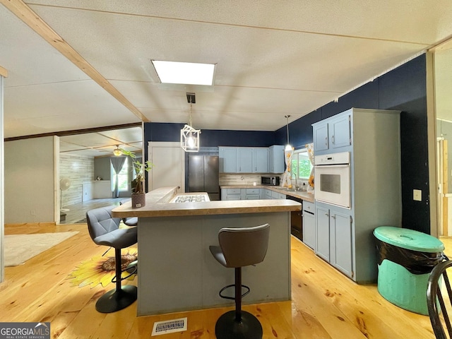 906 Billy Watts Cove Rd, Tiger, GA 30576 - kitchen featuring black appliances, light wood finished floors, a kitchen bar, decorative light fixtures, and lofted ceiling