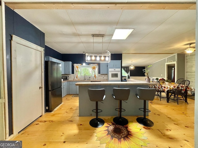 906 Billy Watts Cove Rd, Tiger, GA 30576 - kitchen with freestanding refrigerator, light wood finished floors, light countertops, a breakfast bar, and blue cabinetry