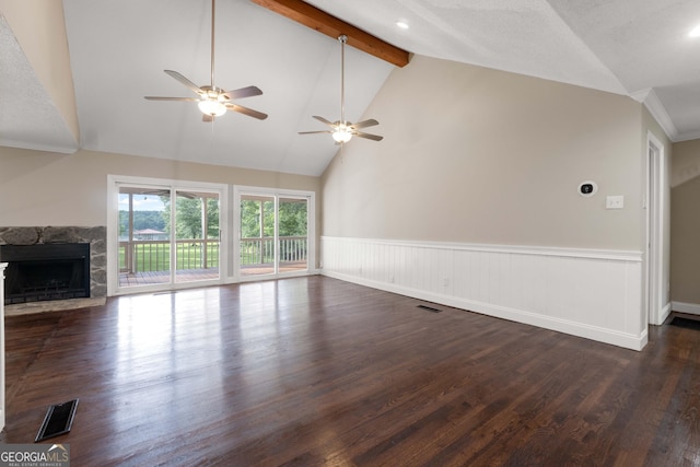 901 Jamesway Dr, Sparta, GA 31087 - unfurnished living room featuring ceiling fan, a stone fireplace, a wainscoted wall, beam ceiling, and dark wood-style flooring