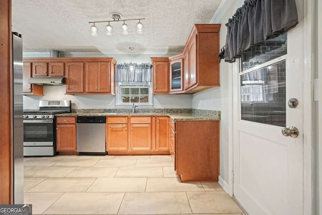 4212 Worth St NW, Acworth, GA 30101 - kitchen with appliances with stainless steel finishes, under cabinet range hood, brown cabinetry, a textured ceiling, and dark stone counters