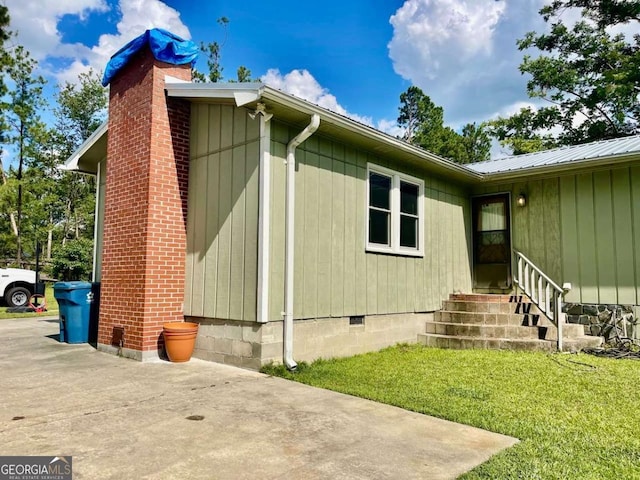 207 Timothy Ct, Vidalia, GA 30474 - view of side of home featuring entry steps, crawl space, a chimney, a lawn, and a metal roof
