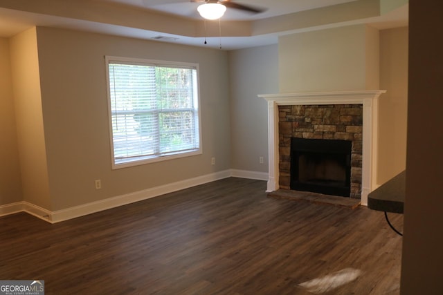 320 Cainbridge Mdws, Demorest, GA 30535 - unfurnished living room featuring ceiling fan, dark wood-style floors, a tray ceiling, and a stone fireplace