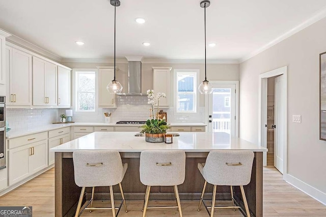 164 Palm St, Holly Springs, GA 30188 - kitchen with wall chimney range hood, tasteful backsplash, a kitchen island with sink, a kitchen breakfast bar, and crown molding