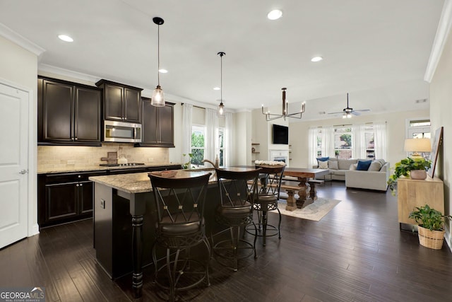 5640 Hammock Way, Cumming, GA 30028 - kitchen featuring stainless steel microwave, gas cooktop, a kitchen breakfast bar, a ceiling fan, and backsplash