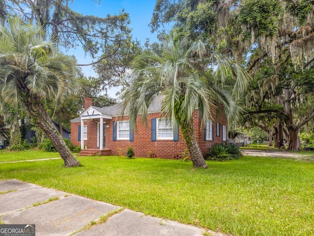 805 First Ave, Brunswick, GA 31520 - view of front of house with a front yard, brick siding, and a chimney