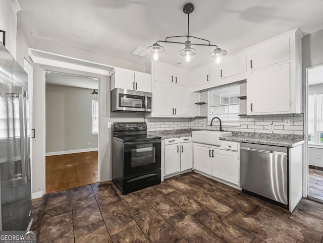 805 First Ave, Brunswick, GA 31520 - kitchen featuring appliances with stainless steel finishes, decorative backsplash, plenty of natural light, and white cabinets