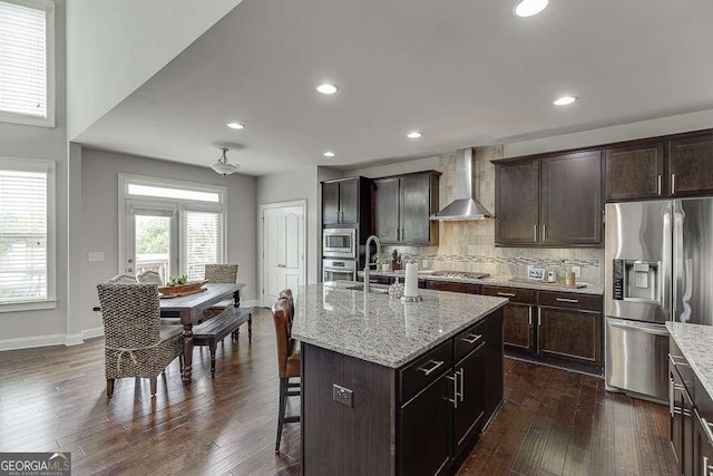 1830 Secretariat Gait Way, Suwanee, GA 30024 - kitchen with appliances with stainless steel finishes, wall chimney exhaust hood, a breakfast bar, dark wood-style floors, and tasteful backsplash