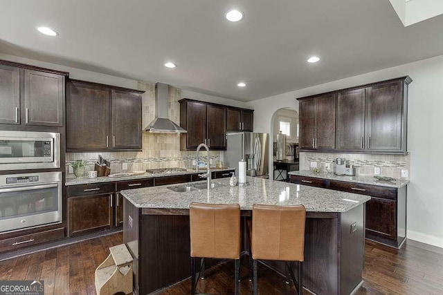 1830 Secretariat Gait Way, Suwanee, GA 30024 - kitchen with appliances with stainless steel finishes, wall chimney exhaust hood, arched walkways, an island with sink, and backsplash
