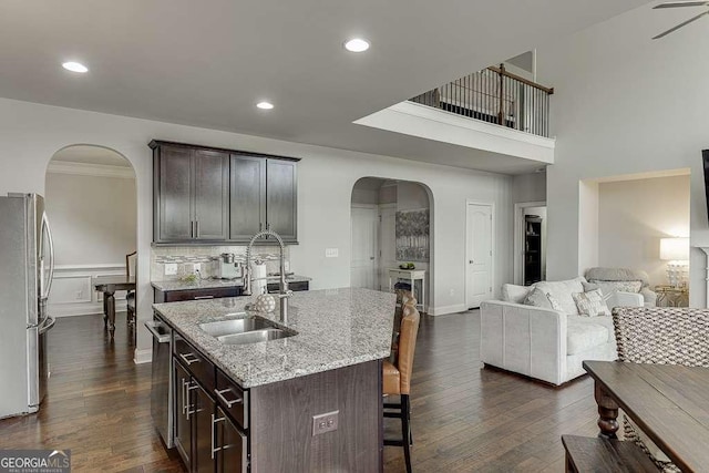 1830 Secretariat Gait Way, Suwanee, GA 30024 - kitchen with appliances with stainless steel finishes, arched walkways, a breakfast bar, light stone counters, and dark brown cabinetry