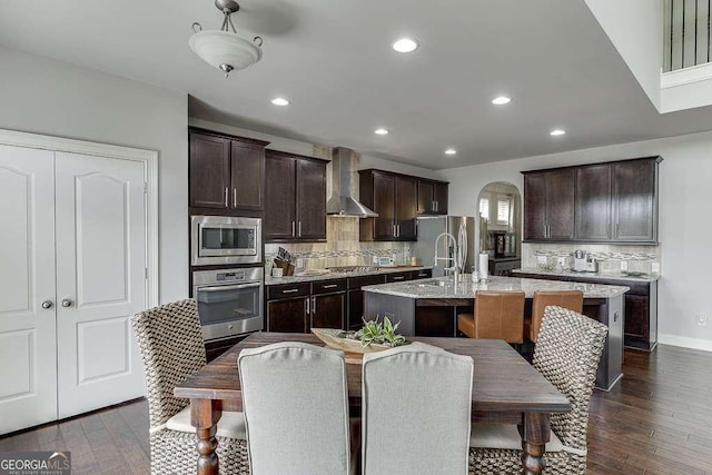 1830 Secretariat Gait Way, Suwanee, GA 30024 - kitchen with stainless steel appliances, wall chimney range hood, a center island with sink, tasteful backsplash, and recessed lighting