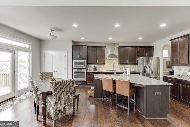 1830 Secretariat Gait Way, Suwanee, GA 30024 - kitchen with stainless steel appliances, wall chimney range hood, decorative backsplash, an island with sink, and recessed lighting