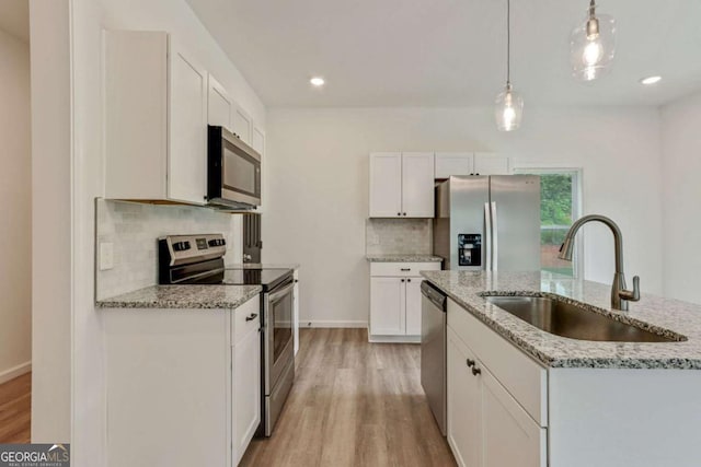 307 E Pine St E, Rockmart, GA 30153 - kitchen featuring appliances with stainless steel finishes, light wood-type flooring, decorative backsplash, decorative light fixtures, and white cabinets
