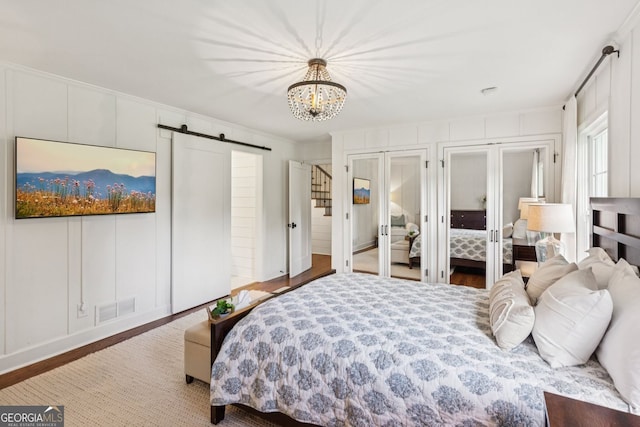 5095 Karr Rd, Cumming, GA 30040 - bedroom with a barn door, multiple closets, wood finished floors, a chandelier, and french doors