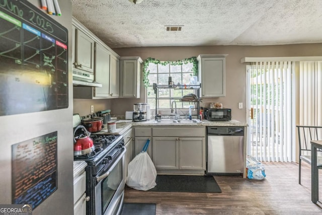 447 Sherwood Cir, Stone Mountain, GA 30087 - kitchen with stainless steel appliances, under cabinet range hood, dark wood finished floors, light countertops, and a textured ceiling