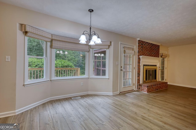 120 Fox Hunt Pl, Athens, GA 30606 - unfurnished living room with wood finished floors, healthy amount of natural light, a chandelier, a textured ceiling, and a fireplace
