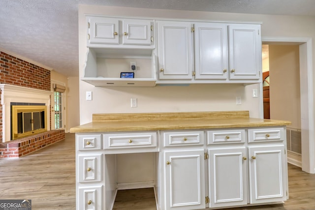 120 Fox Hunt Pl, Athens, GA 30606 - kitchen featuring light countertops, light wood finished floors, a textured ceiling, open shelves, and a fireplace