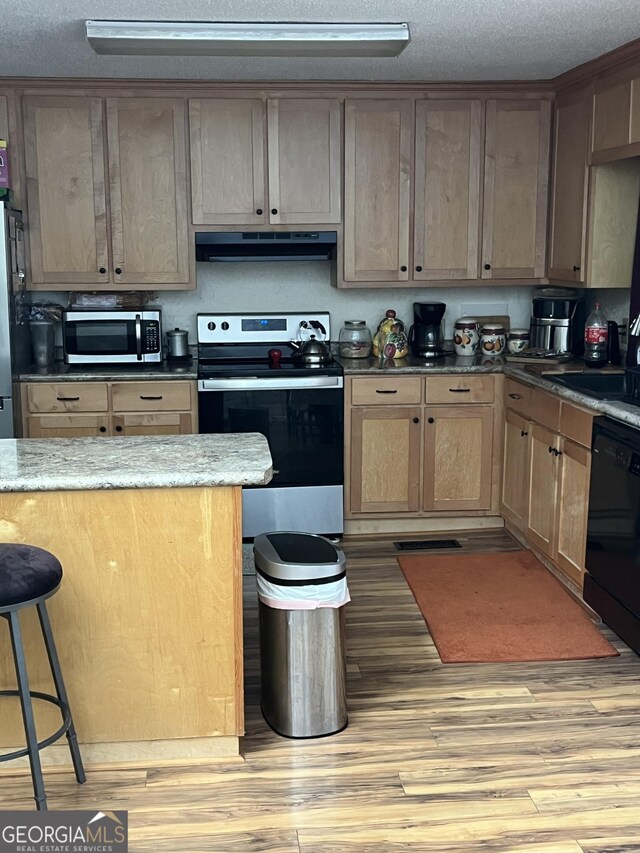 17 Dime St, Douglas, GA 31535 - kitchen with stainless steel appliances, under cabinet range hood, light wood finished floors, a kitchen bar, and a textured ceiling