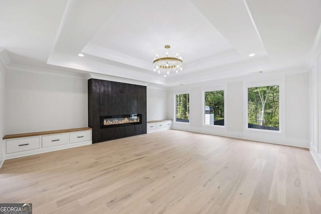 3205 Bold Springs Rd, Dacula, GA 30019 - unfurnished living room featuring a tray ceiling, light wood-type flooring, a fireplace, a chandelier, and ornamental molding