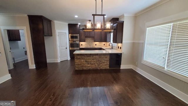 90 Alcovy Reserve Way, Covington, GA 30014 - kitchen with appliances with stainless steel finishes, a peninsula, dark wood-style flooring, dark brown cabinetry, and decorative backsplash