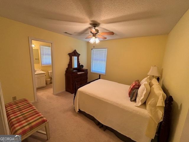 42 Lagoon Rd, Statesboro, GA 30461 - bedroom with light carpet, connected bathroom, a ceiling fan, and a textured ceiling