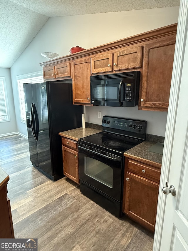 330 Anchors Way, Winder, GA 30680 - kitchen featuring black appliances, light wood-type flooring, a textured ceiling, dark countertops, and lofted ceiling