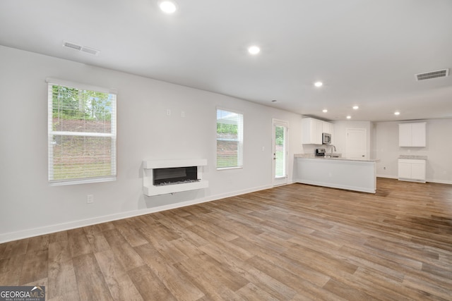 1184 Bluecoat Cir Unit 84, Hampton, GA 30228 - unfurnished living room with light wood-style flooring, recessed lighting, healthy amount of natural light, and a fireplace