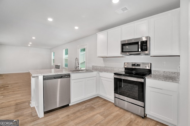1184 Bluecoat Cir Unit 84, Hampton, GA 30228 - kitchen with stainless steel appliances, a peninsula, light wood-type flooring, white cabinetry, and recessed lighting