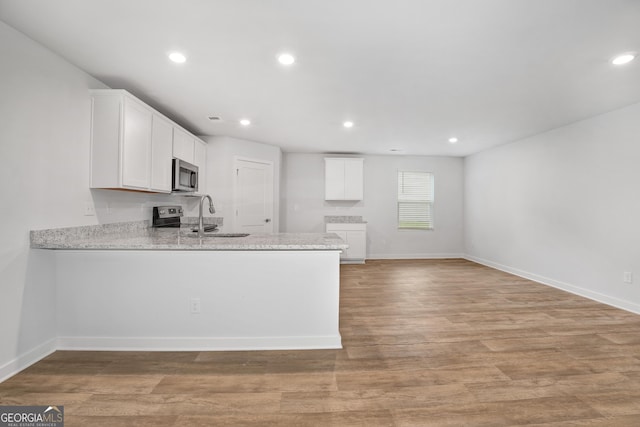 1184 Bluecoat Cir Unit 84, Hampton, GA 30228 - kitchen with stainless steel microwave, a peninsula, white cabinetry, light wood-style floors, and recessed lighting