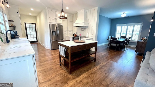 420 Ashbury Cir, Dallas, GA 30157 - kitchen with stainless steel fridge, custom range hood, wood finished floors, white cabinetry, and light stone counters