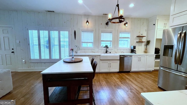 420 Ashbury Cir, Dallas, GA 30157 - kitchen with stainless steel appliances, a chandelier, light wood finished floors, white cabinets, and wood walls