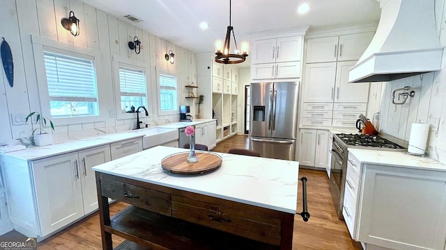 420 Ashbury Cir, Dallas, GA 30157 - kitchen with stainless steel appliances, custom range hood, light wood-style floors, light stone counters, and white cabinetry