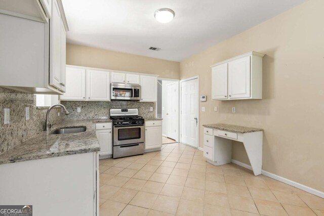 5035 Foxberry Ln, Roswell, GA 30075 - kitchen with appliances with stainless steel finishes, decorative backsplash, white cabinets, light stone counters, and light tile patterned floors