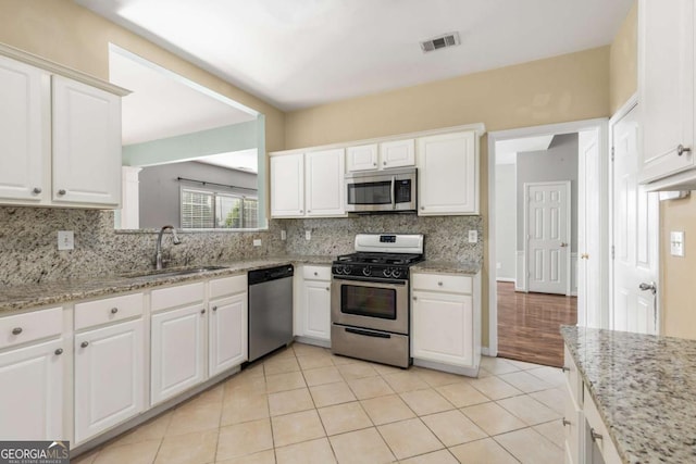 5035 Foxberry Ln, Roswell, GA 30075 - kitchen featuring appliances with stainless steel finishes, decorative backsplash, white cabinetry, and light tile patterned floors