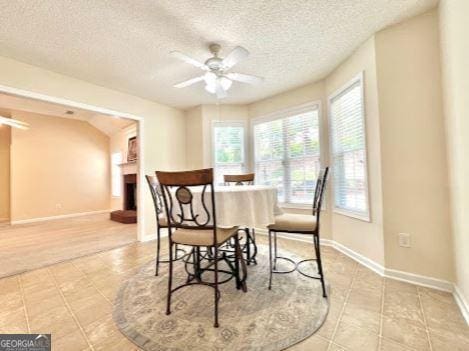 121 Pinnacle Ln, Mcdonough, GA 30253 - dining room with a ceiling fan, a textured ceiling, light tile patterned floors, and a fireplace with raised hearth